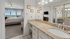 A bedroom with a bed, a bathroom with a sink and mirror, and a ceiling fan. - Edgewater 304 Sandy Beach and a heated swimming pool. (South Padre Island)