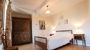 Un dormitorio con cama y mesita de noche de madera, una silla, un armario y una lámpara en el techo.