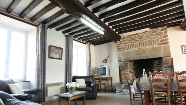 Una sala de estar con chimenea, un sofá, un televisor y un comedor con sillas y una mesa.