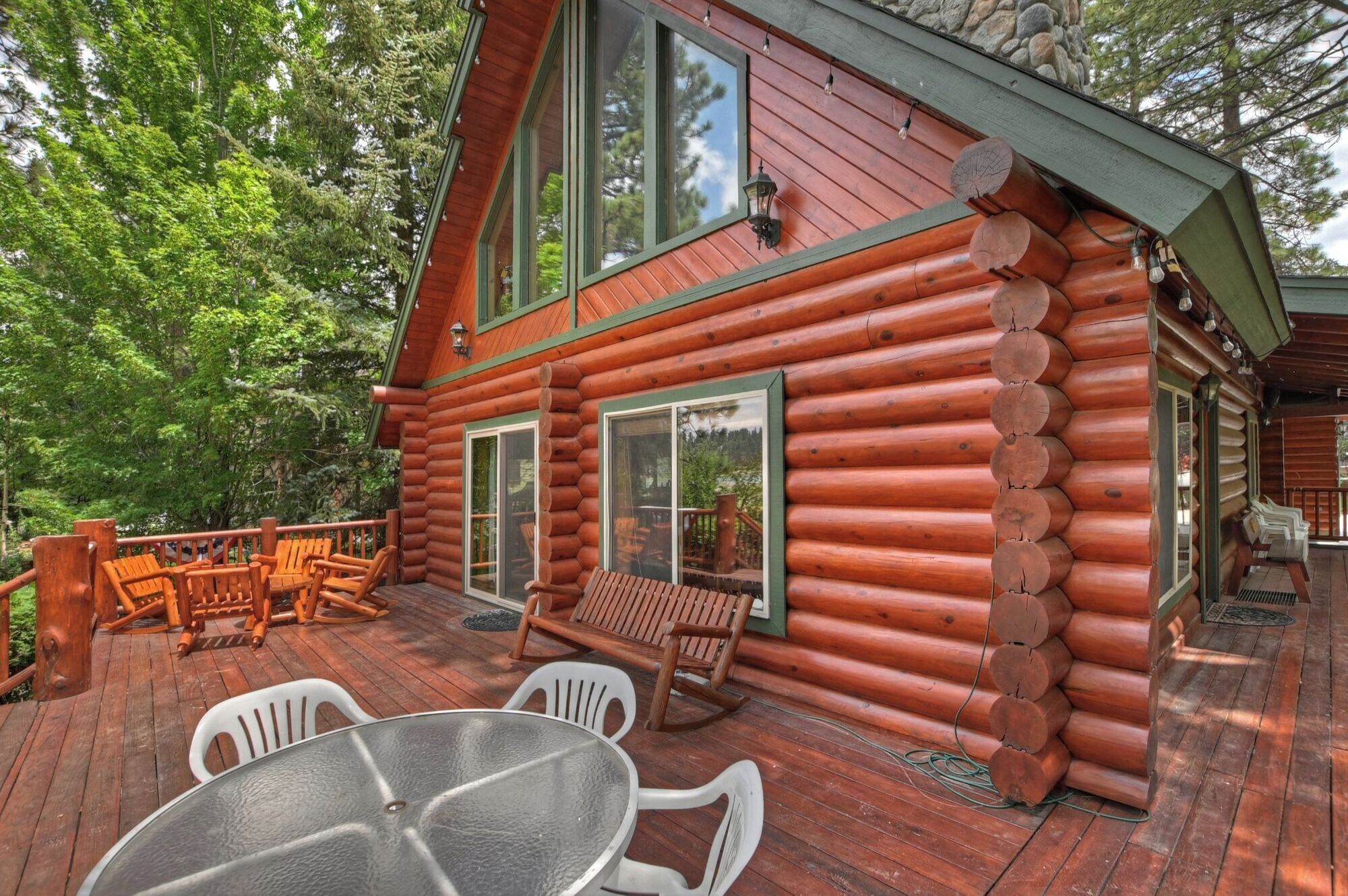 Een houten chalet met terras, buitenmeubels en grote ramen.