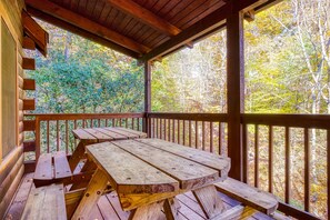 Una terraza de madera con mesas de picnic y vistas al follaje otoñal.