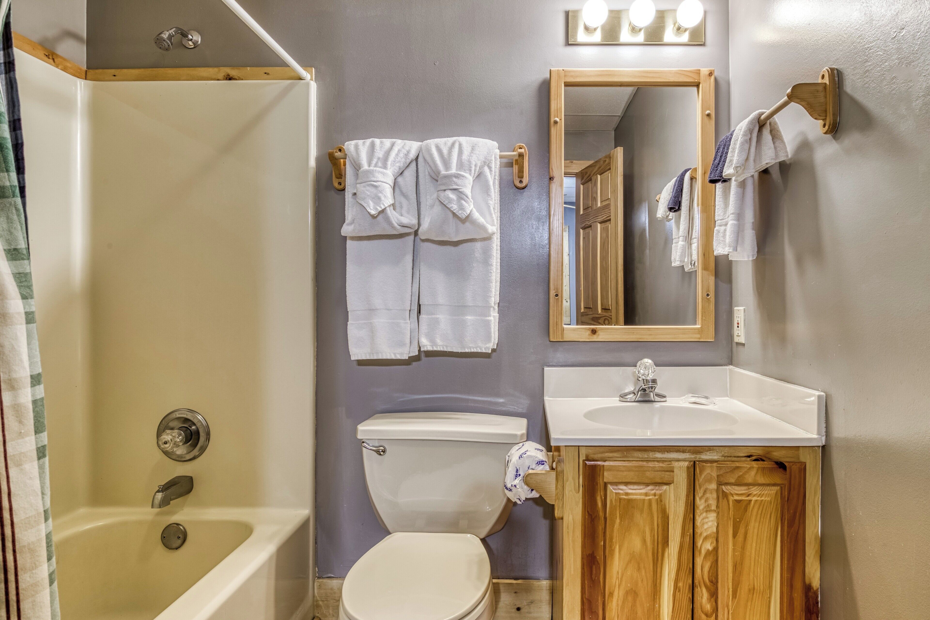 Ein Badezimmer mit Badewanne, Toilette, Waschbecken und Holzschränken.
