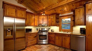 Una cocina con armarios de madera, electrodomésticos de acero inoxidable y piso de baldosas.