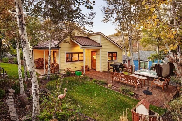 Une maison avec une terrasse, un barbecue et un jacuzzi.