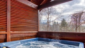 A hot tub with a view of trees and mountains through a wooden structure. - Point Of View - Spacious 2 Bedroom With a Loft Just off Glades Road (Gatlinburg)