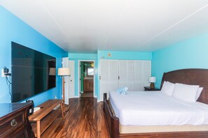 Ein Hotelzimmer mit einem großen Bett, einem Schreibtisch, einem Fernseher und einem durch eine offene Tür einsehbarer Badezimmer.