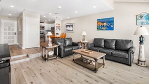 A modern living room with a leather sofa, wooden coffee table, and a dining area with a table and chairs. - 2B | 2B Villa, 6-seat cart, panoramic ocean views, AC (Avalon)