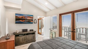 A bedroom with a large bed, a TV on a wooden cabinet, a sailboat model, and a scenic painting. - 2B | 2B Villa, 6-seat cart, panoramic ocean views, AC (Avalon)