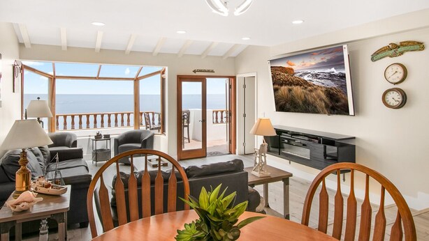 A spacious living area with a view of the sea, a dining table with chairs, a sofa, and a TV. - 2B | 2B Villa, 6-seat cart, panoramic ocean views, AC (Avalon)