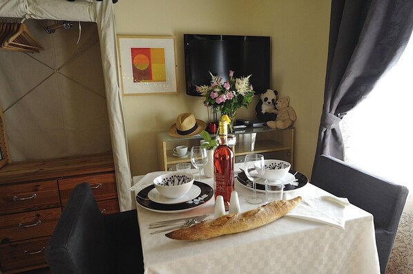 A dining table set with plates, bowls, a bottle, and a baguette. - A4DF Syracuse (París)