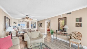 A spacious living room with a sofa, coffee table, and a dining area in the background. -  🌊 Islander #508 – Beachfront Bliss with Amazing Views! 🏖️✨ (Destin)