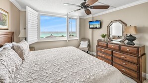 A bedroom with a large bed, a ceiling fan, a dresser, a TV, and a window with a view of the ocean. - 🌊 Islander #508 – Beachfront Bliss with Amazing Views! 🏖️✨ (Destin)