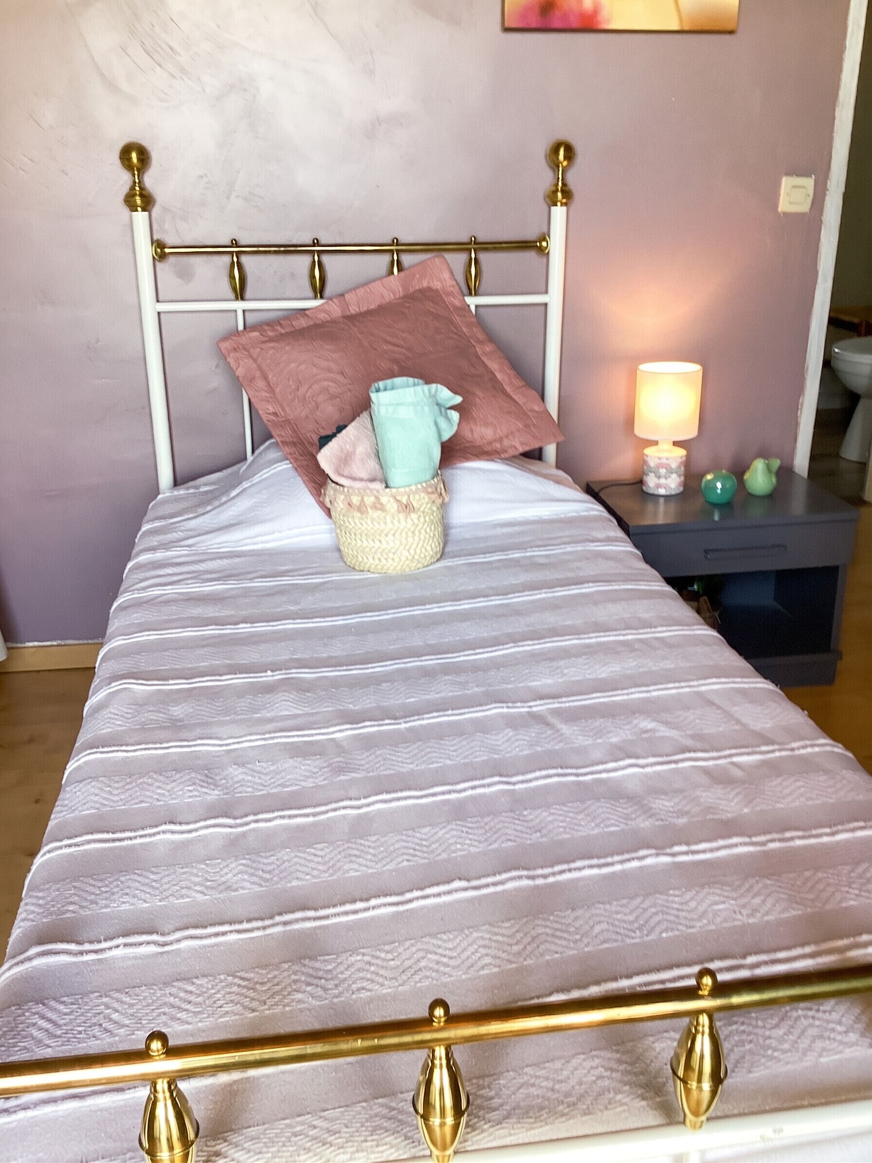 A bed with a headboard, a bedside table with a lamp, and a small decorative item.