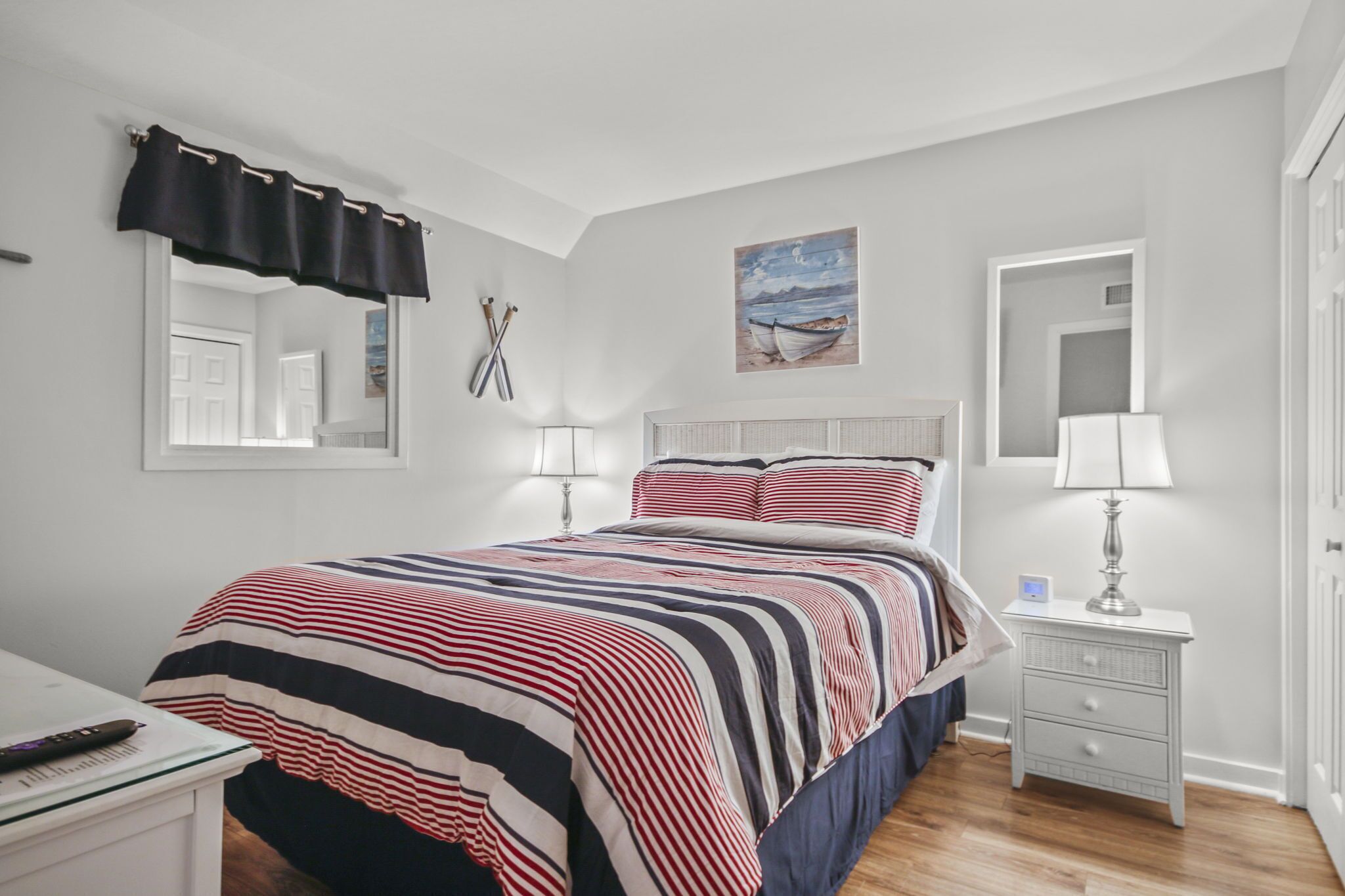 Une chambre à coucher avec un lit, des tables de chevet, un miroir et un tableau au mur.