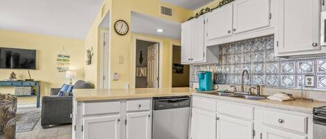 A kitchen with white cabinets, a dishwasher, and a tiled backsplash.
