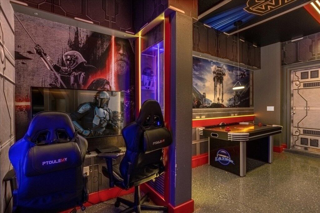 Una sala giochi con due poltrone gaming PTSULEMY, un tavolo da calcio e arredamento a tema Star Wars.