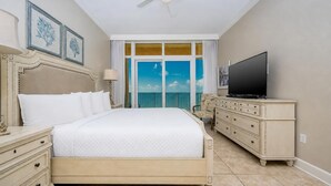 Una habitación de hotel con cama, televisor, cómoda y balcón con vistas.