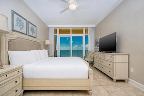 A hotel room with a bed, a television, a dresser, and a balcony with a view.