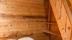 A wooden bed with a headboard in a cabin-style room.