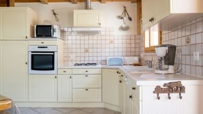 A kitchen with white cabinetry, a microwave, an oven, a toaster, and a coffee maker.