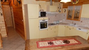 A kitchen with a wooden table, a microwave, an oven, and a sink.