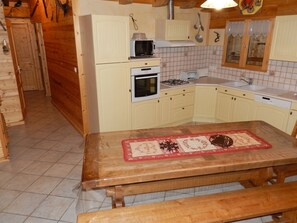 A kitchen with a wooden table, a microwave, an oven, and a sink. - Homerez - Apartment Hauteluce, mountain view (Hauteluce)