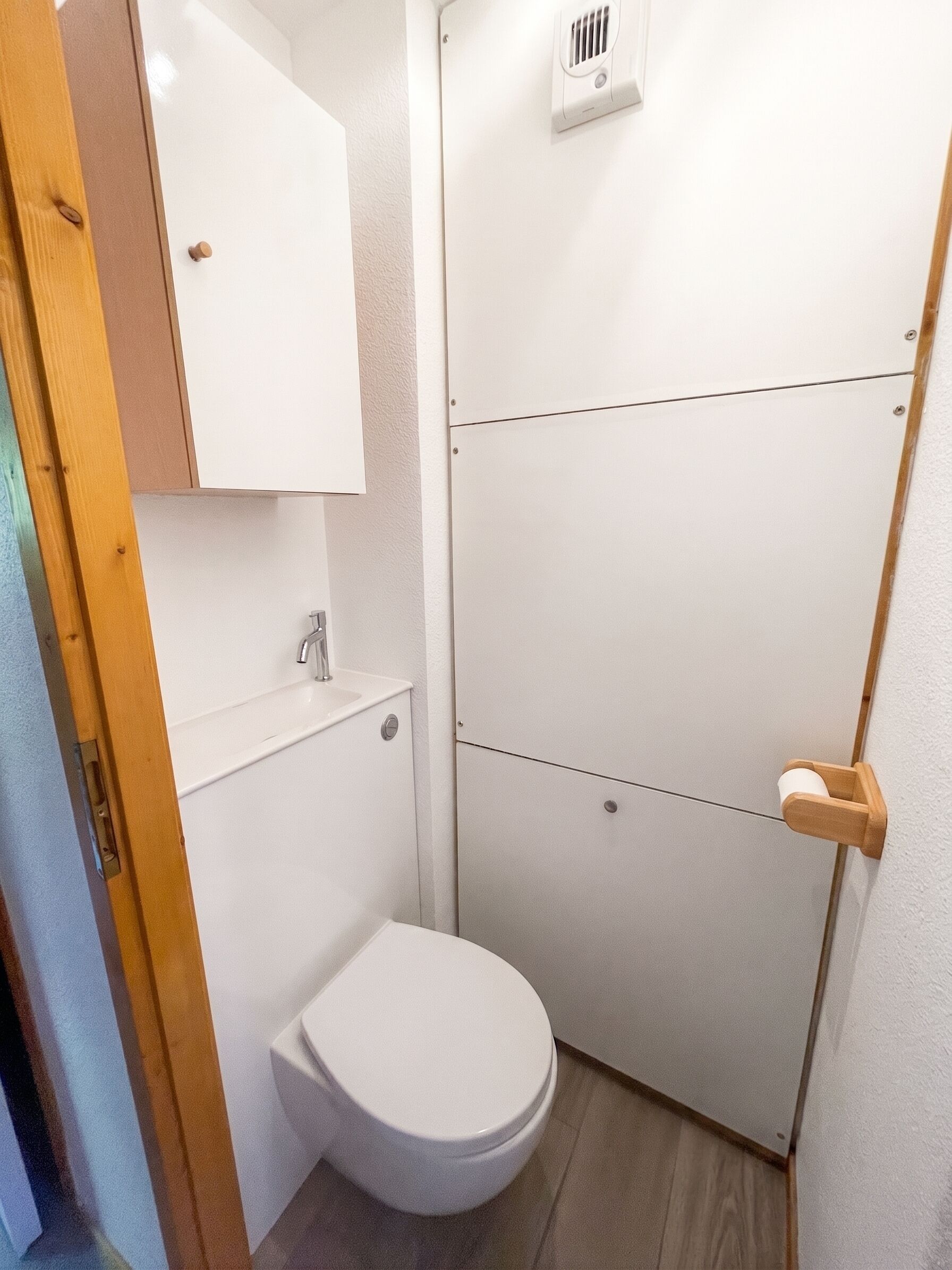 Et lille badeværelse med toilet, håndvask og brusekabine.