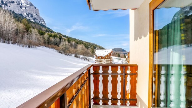 Ein Balkon mit Blick auf eine verschneite Landschaft und einen Berg.