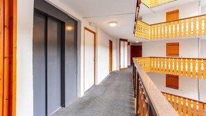 Ein Hotelkorridor mit Teppichboden, Holzhandläufen und Türen zu Zimmern.