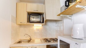 Eine kleine Küche mit eingebautem Toaster, einer Mikrowelle und einer Kaffeemaschine auf einem Regal.