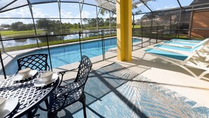 A covered outdoor area with a pool, lounge chairs, and a table with chairs and cups. - Lake View! Amazing Sunsets w/West Facing Pool (Clermont)