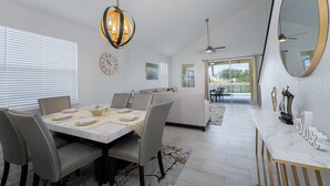A dining area with a marble table, grey upholstered chairs, a chandelier, and a large mirror on the wall. - Lake View! Amazing Sunsets w/West Facing Pool (Clermont)