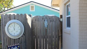 Une porte en bois ornée d’une horloge, une pancarte sur laquelle on peut lire « Que Dieu bénisse l’Amérique », et une maison à l’extérieur bleu.