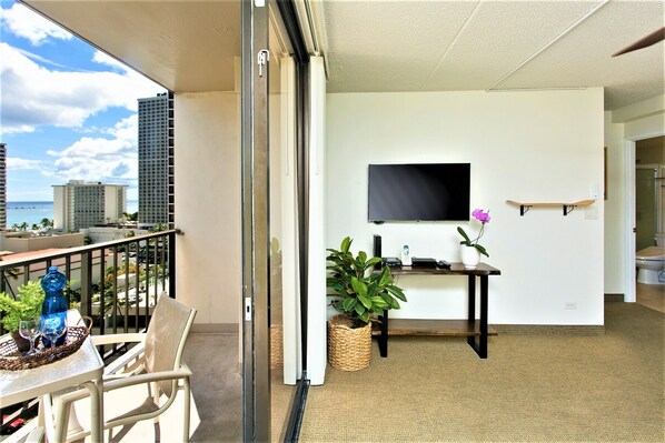 A balcony with a table, chairs, and a potted plant.