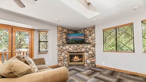 Una sala de estar con chimenea de piedra, un sofá y un televisor montado en la pared.