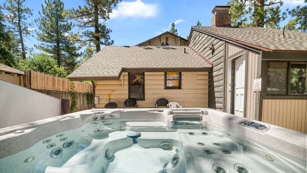 Un jacuzzi en un patio trasero con una casa de madera al fondo.