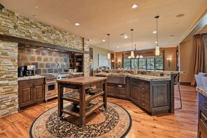 A kitchen with a stone backsplash, wooden cabinets, a central island, and a large window.