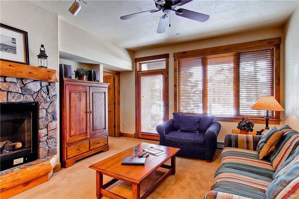 A cozy living room with a fireplace, wooden cabinets, a sofa, and a coffee table.