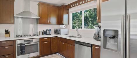 Una cocina moderna con armarios de madera, electrodomésticos de acero inoxidable y un dispensador de agua integrado.