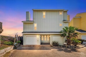 A two-story house with a garage, a front porch, and a small patio area.