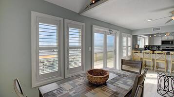 A spacious kitchen with modern appliances, a dining area with a large table, and a view of the ocean through large sliding doors.