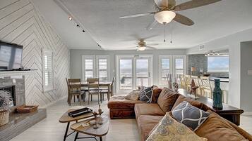 A spacious living room with a fireplace, a large sofa, and a dining area.