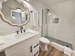 A modern bathroom with a white vanity, a large mirror, a toilet, and a shower area. - Ariel Dunes 2005 | Gulf Views from 20th Floor | Fully Renovated | Zero-Entry Pool (Miramar Beach)