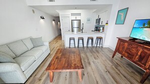 Un salon moderne avec une table basse en bois, un canapé gris et un meuble en bois sur lequel est posée une télévision.