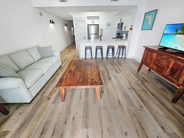 A modern living room with a wooden coffee table, a grey sofa, and a wooden cabinet with a TV.