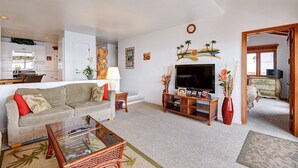 A living room with a sofa, coffee table, TV, and decorative items. - H230: Comfortable 2BD Villa w/ Ocean Views, WIFI, 4-seat Golf Cart (Avalon)