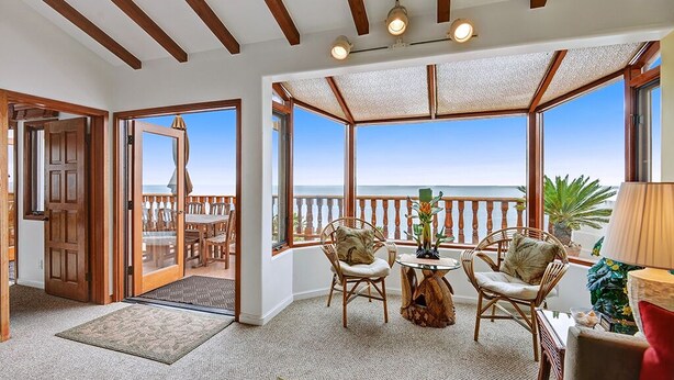 A room with a view of the sea, wooden ceiling beams, a dining area with chairs, and a table with a vase. - H230: Comfortable 2BD Villa w/ Ocean Views, WIFI, 4-seat Golf Cart (Avalon)