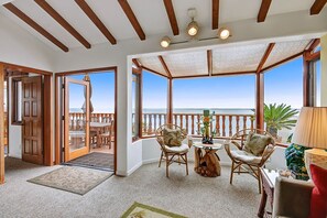 A room with a view of the sea, wooden ceiling beams, a dining area with chairs, and a table with a vase. - H230: Comfortable 2BD Villa w/ Ocean Views, WIFI, 4-seat Golf Cart (Avalon)