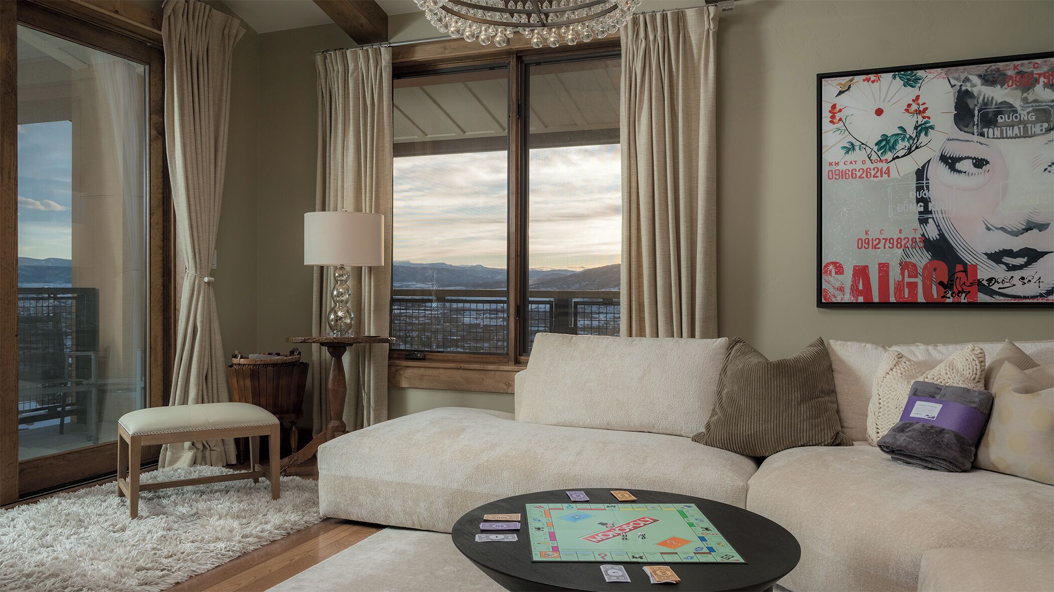 A modern living room with a large window, a sofa, a coffee table with board games, and a lamp.