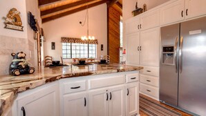 A kitchen with white cabinets, a marble countertop, and a stainless steel refrigerator.